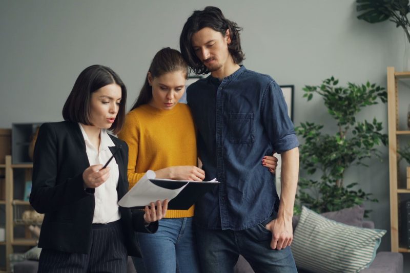 Home 13 A couple reviewing documents with a real estate agent indoor 1781629493